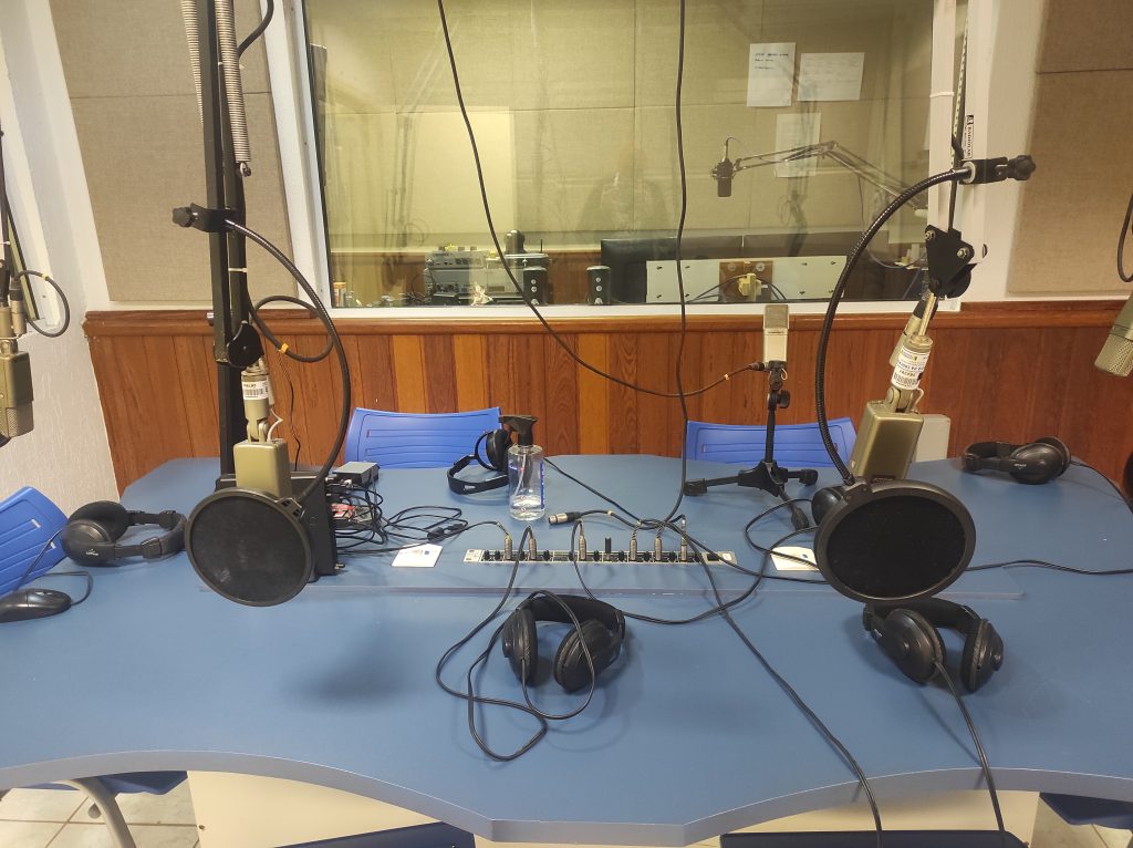 Mesa com fones e microfones do laboratório de radiojornalismo