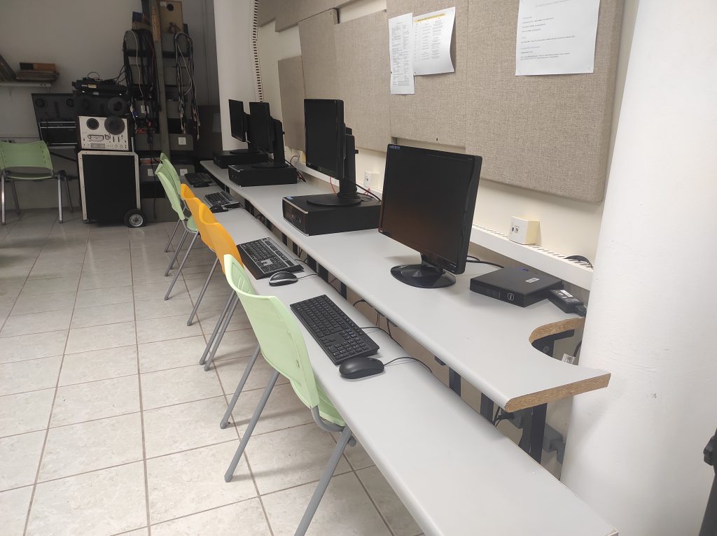 Sala de aula com uma mesa e computadores